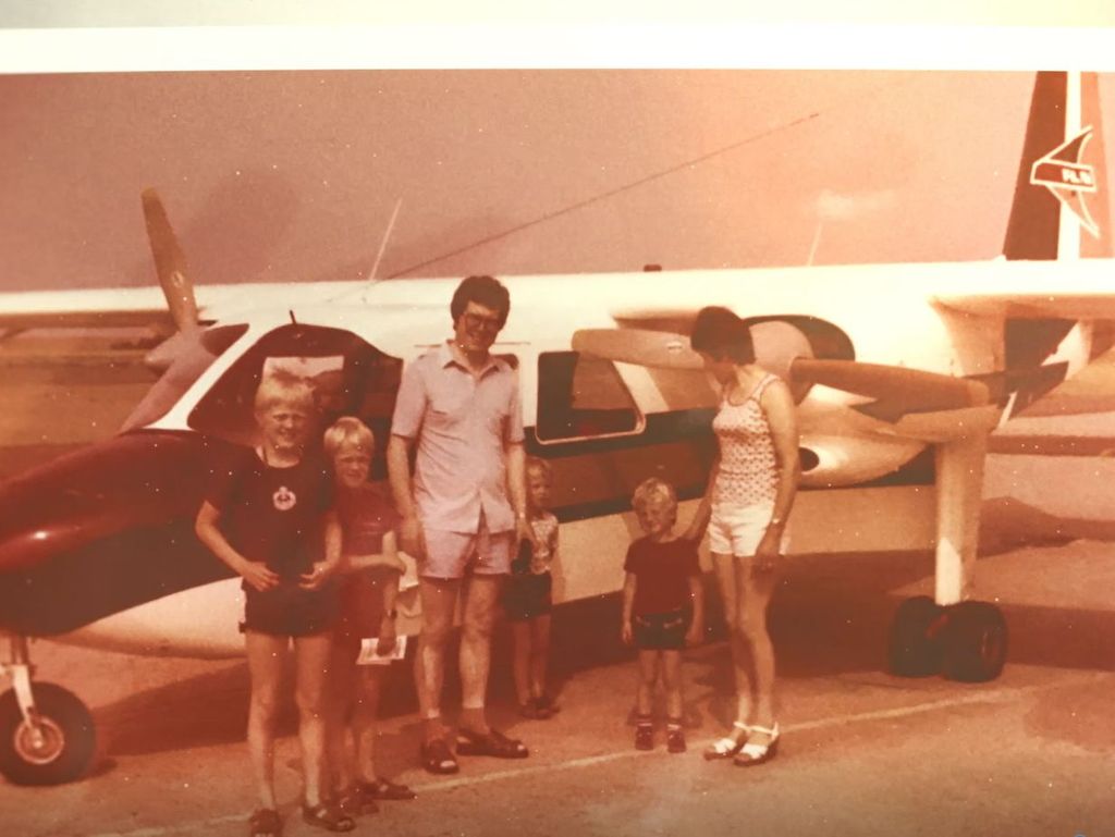 Eine Familie steht auf einem alten Foto vor einem Flugzeug