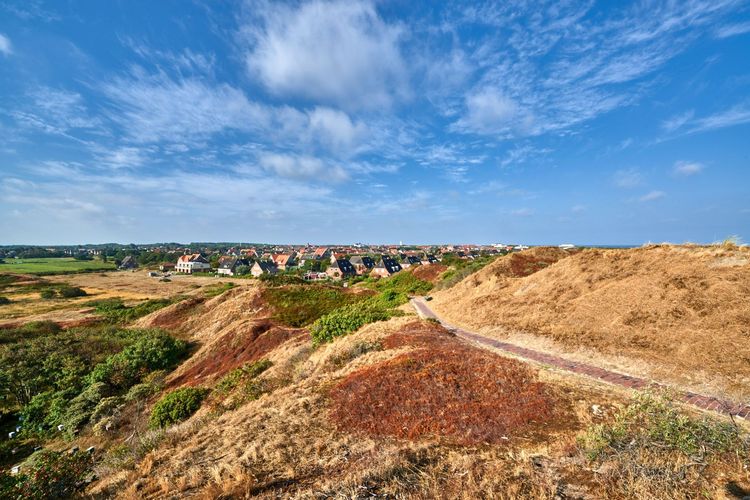Blauer Himmel über Dünen und Häusern des Inselkerns auf Langeoog