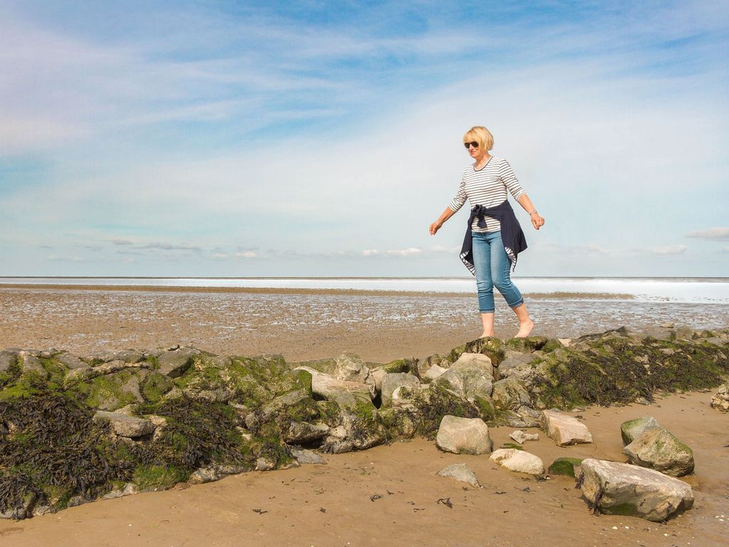 Eine Frau läuft auf Steinen im Wattenmeer während einer Wanderung 