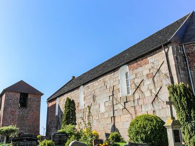 Außenansicht der alten Steinwand der Kirche Buttforde mit Friedhof
