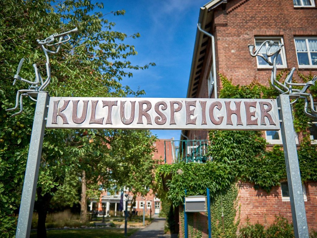 Ein Metallschild mit der Aufschrift "Kulturspeicher" vor dem selbigen Gebäude