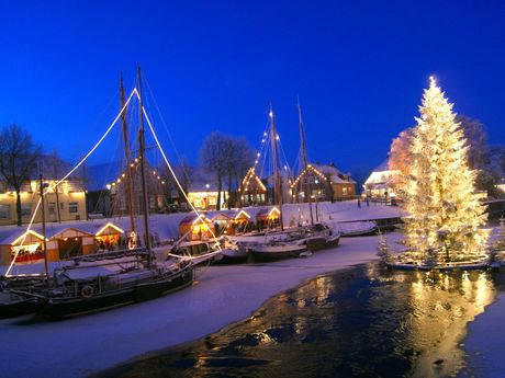schwimmender Weihnachtsbaum im verschneiten Hafen 