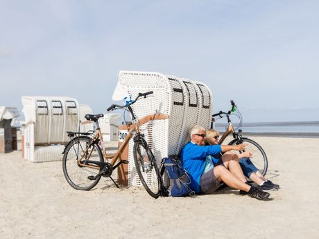 Radfahrer am Strand von Norddeich, im Hintergrund das Wattenmeer