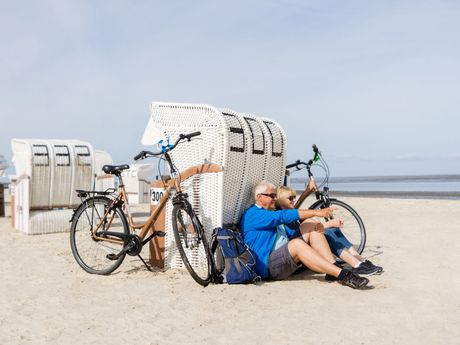 Radfahrer am Strand von Norddeich, im Hintergrund das Wattenmeer