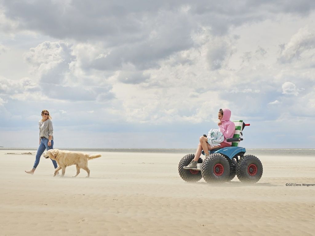 Frau fährt mit dem Strandmobil über den Strand von Langeoog